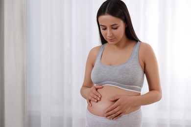 Beautiful pregnant woman in comfortable maternity underwear indoors, space for text