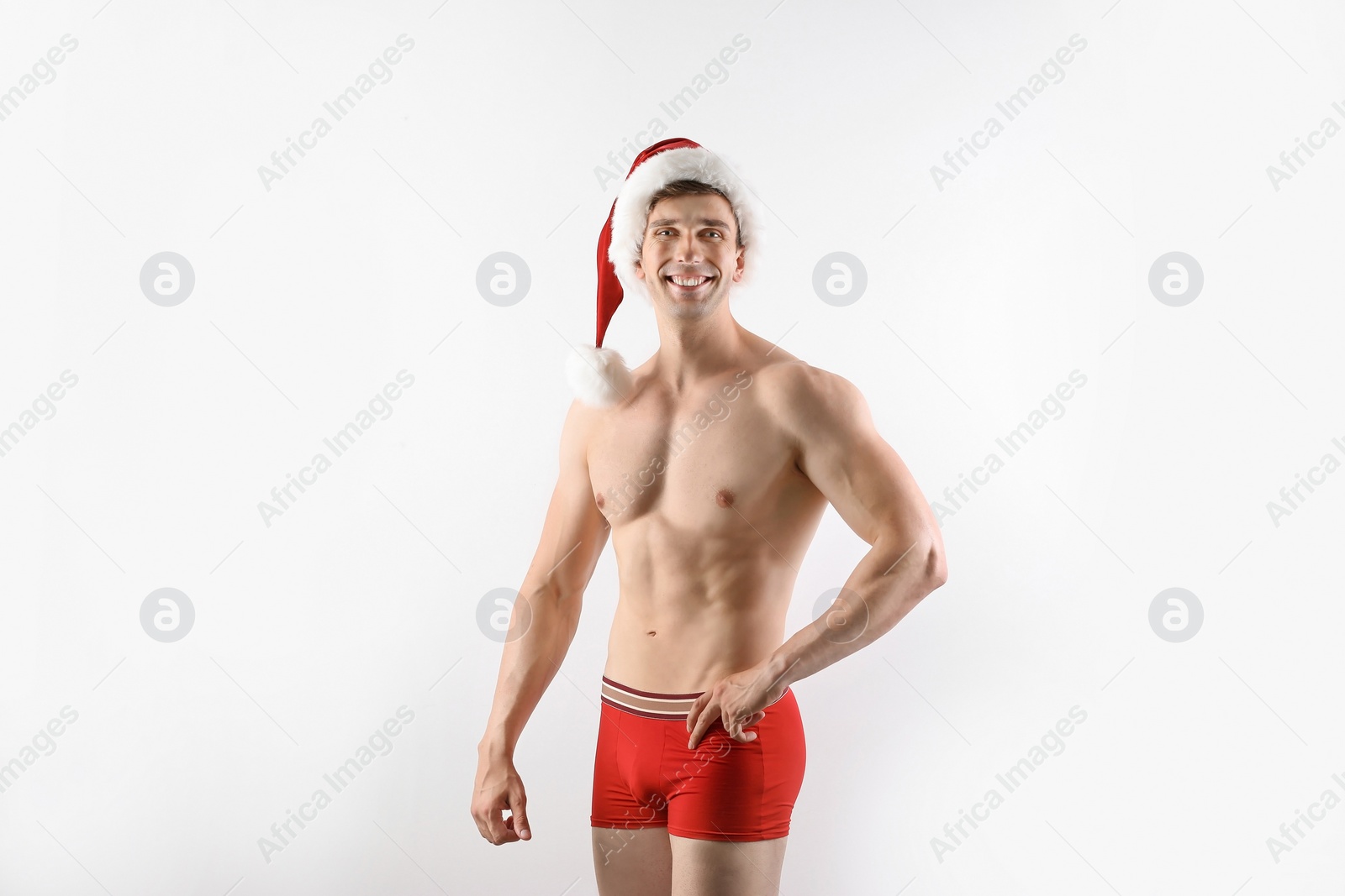 Photo of Young muscular man in Santa hat on white background