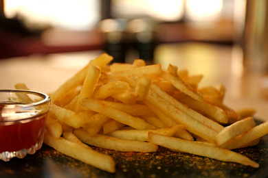 Photo of Delicious hot french fries with red sauce served on table, closeup