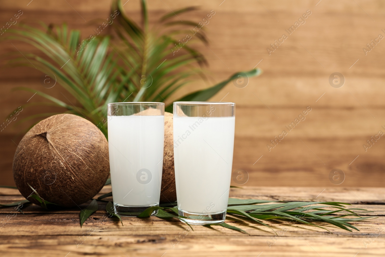 Photo of Composition with glasses of coconut water on wooden background. Space for text