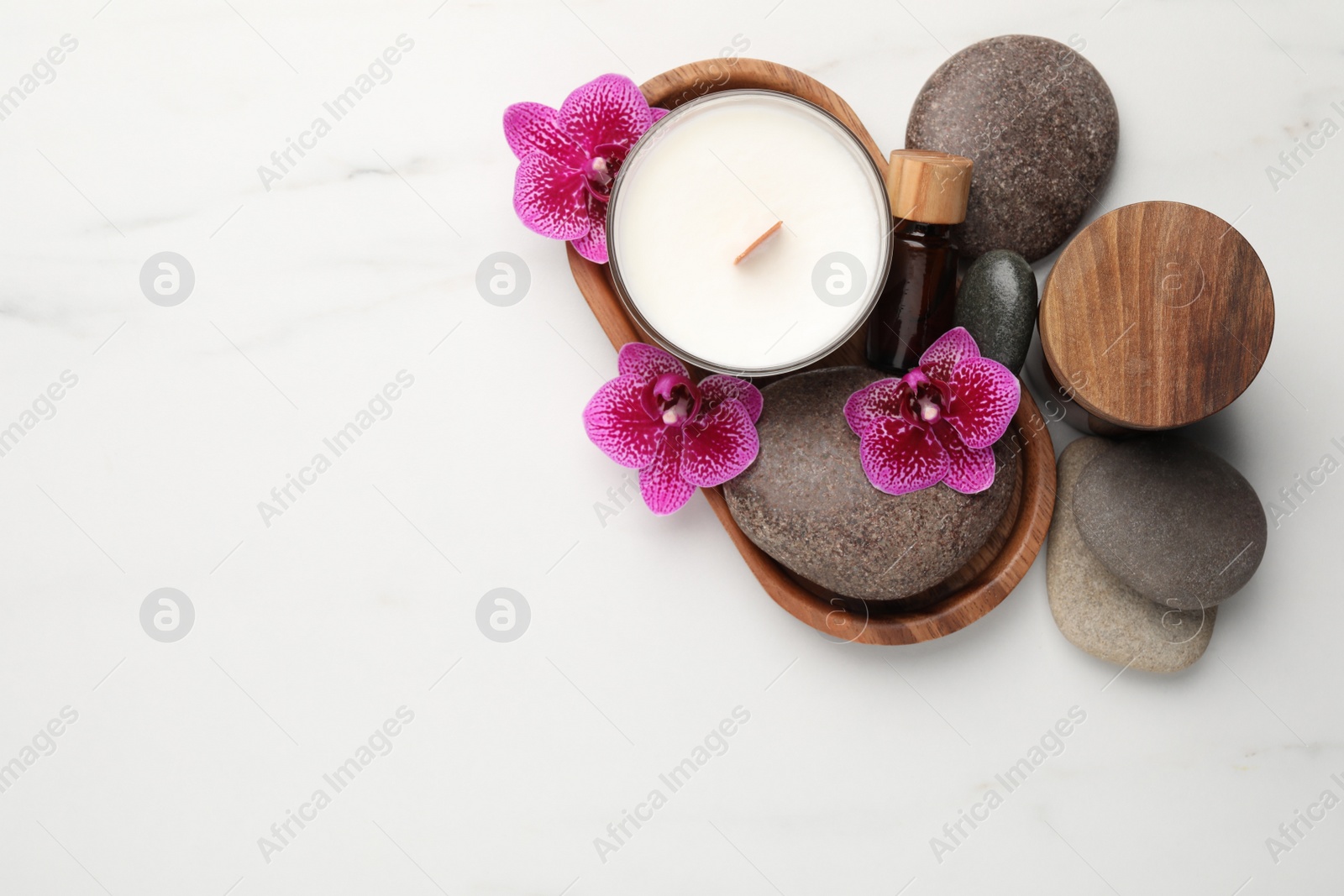 Photo of Flat lay composition with spa stones, candle and orchid flowers on white marble table. Space for text