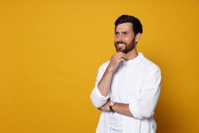 Portrait of smiling bearded man with wristwatch on orange background. Space for text