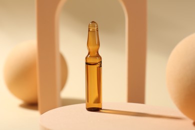 Stylish presentation of glass ampoule with liquid on beige background