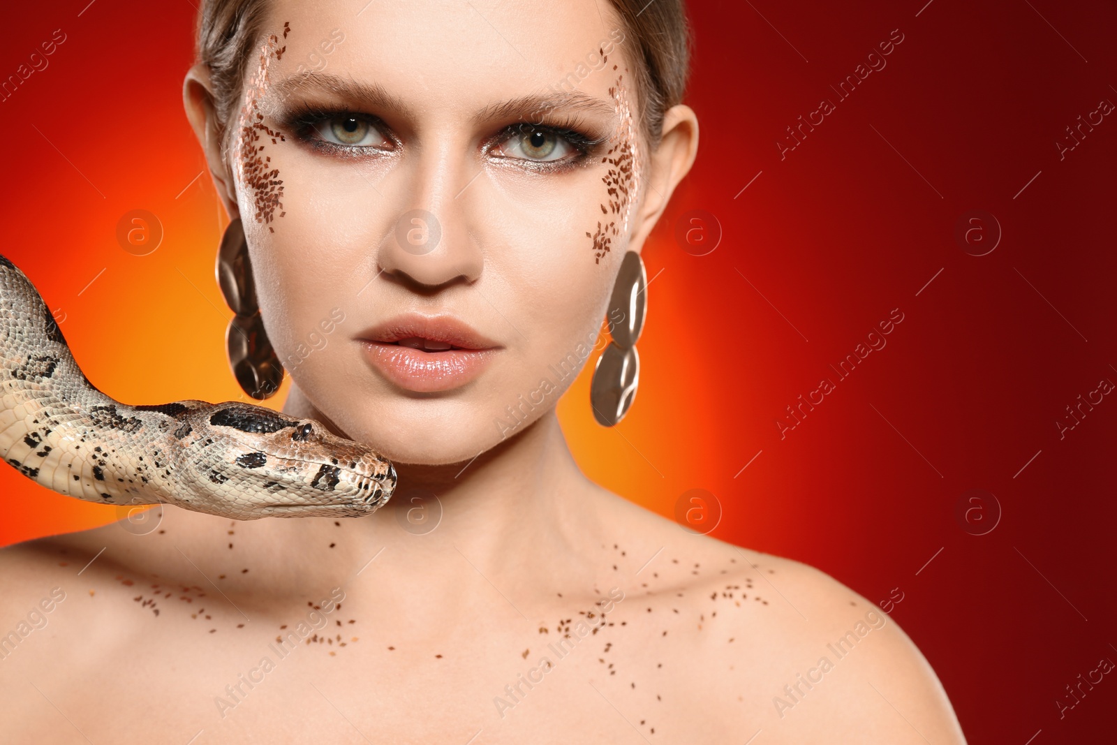 Photo of Beautiful woman with boa constrictor on bright colorful background, closeup