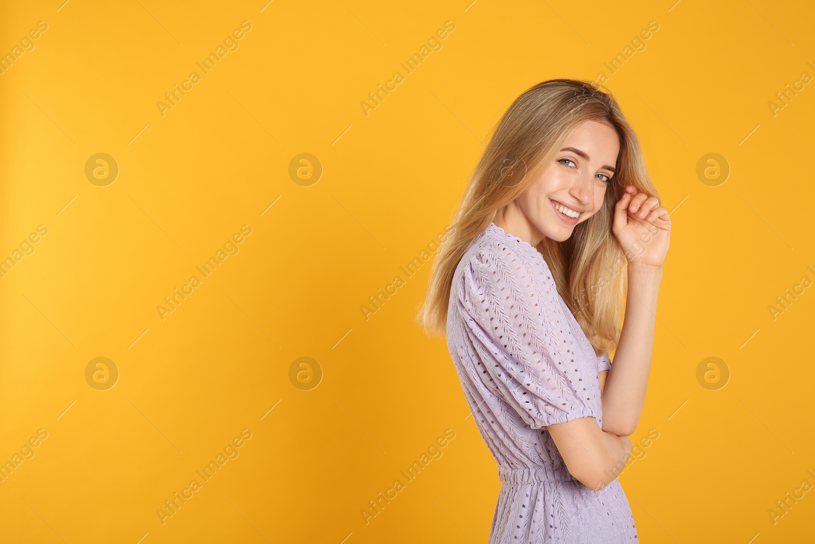 Photo of Beautiful young woman with blonde hair on yellow background. Space for text