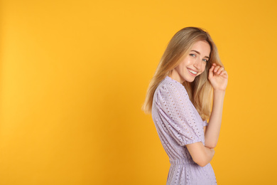 Beautiful young woman with blonde hair on yellow background. Space for text