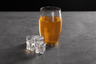 Photo of Energy drink in glass and ice cubes on grey table