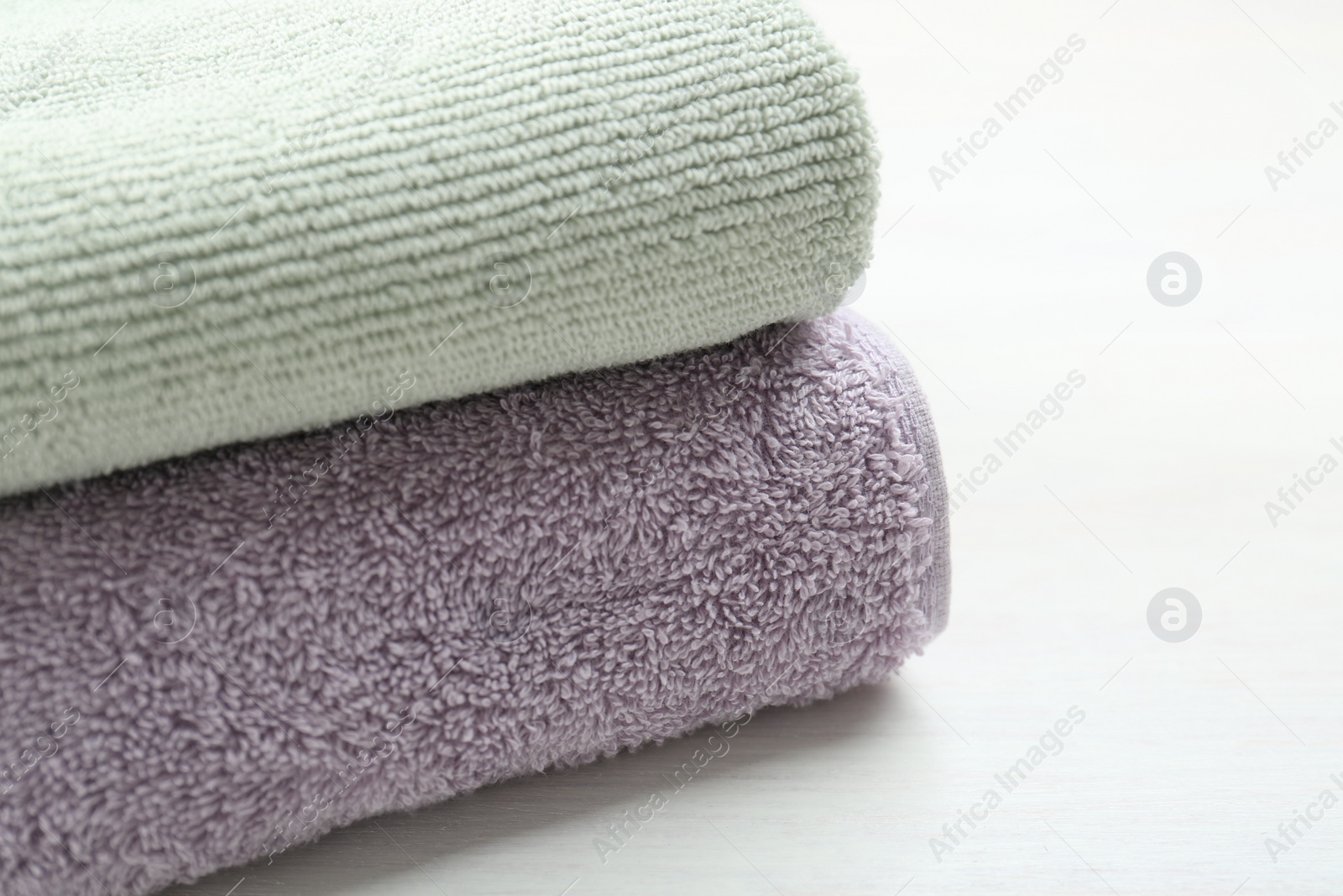 Photo of Different folded towels on white wooden table, closeup. Space for text