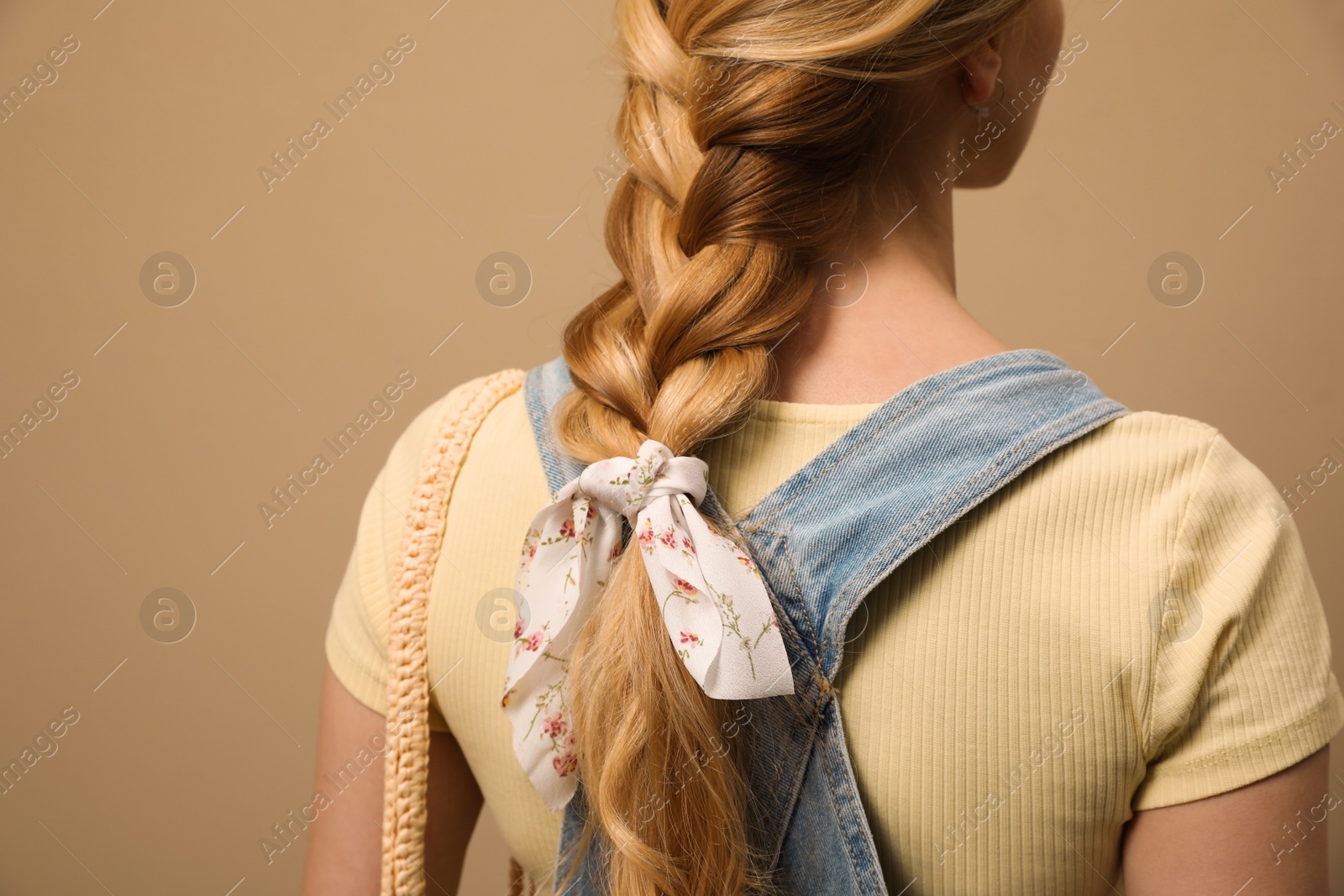 Photo of Young woman with stylish bandana on beige background, closeup