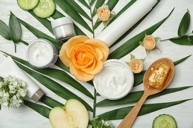 Photo of Beautiful composition with cosmetics, flowers and products on white wooden background, flat lay