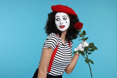 Photo of Funny mine with red rose posing on light blue background