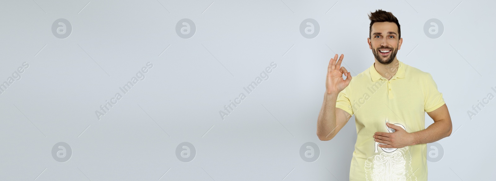 Image of Happy man with healthy digestive system on light grey background, banner design with space for text. Illustration of gastrointestinal tract