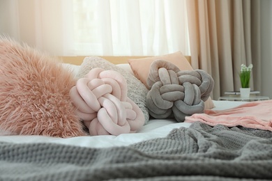 Cozy bed with different pillows and plaid in light room. Idea for interior decor