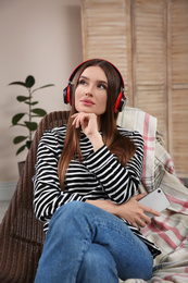 Photo of Woman listening to audiobook in chair at home