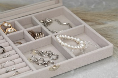 Photo of Jewelry box with many different accessories on light grey table, closeup