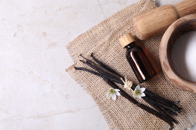 Photo of Vanilla pods, essential oil, flowers and sugar in bowl on light gray table, flat lay. Space for text