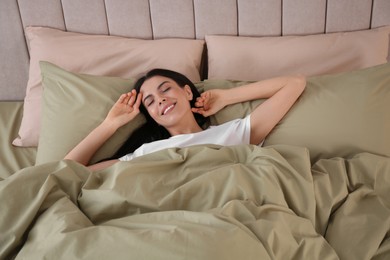 Photo of Woman sleeping in comfortable bed with green linens