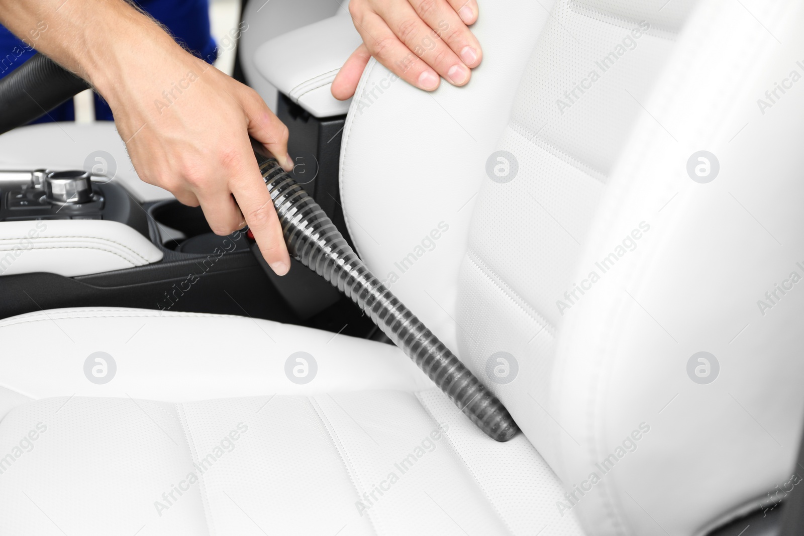 Photo of Man using vacuum cleaner in auto, closeup. Car wash