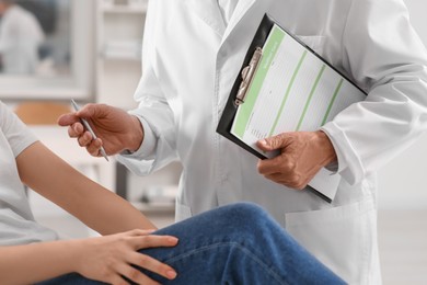 Photo of Doctor with medical card consulting patient in clinic, closeup