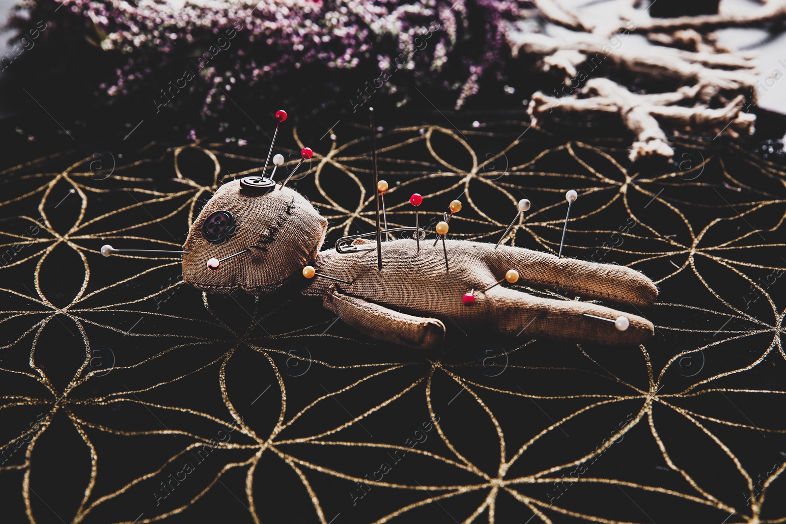 Image of Voodoo doll pierced with pins on table. Curse ceremony