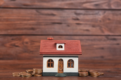 Photo of House model and coins on wooden background