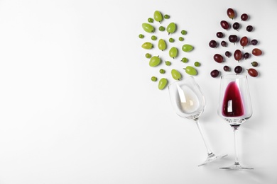 Fresh ripe juicy grapes and glasses of wine on white background, top view