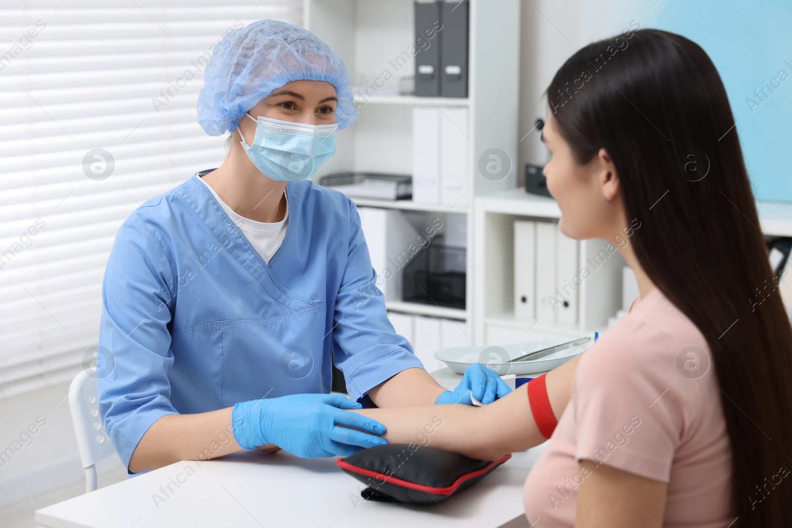 Photo of Laboratory testing. Doctor taking blood sample from patient at white table in hospital