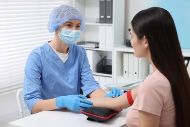 Laboratory testing. Doctor taking blood sample from patient at white table in hospital