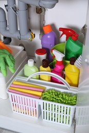 Open under sink cabinet with different cleaning supplies in kitchen