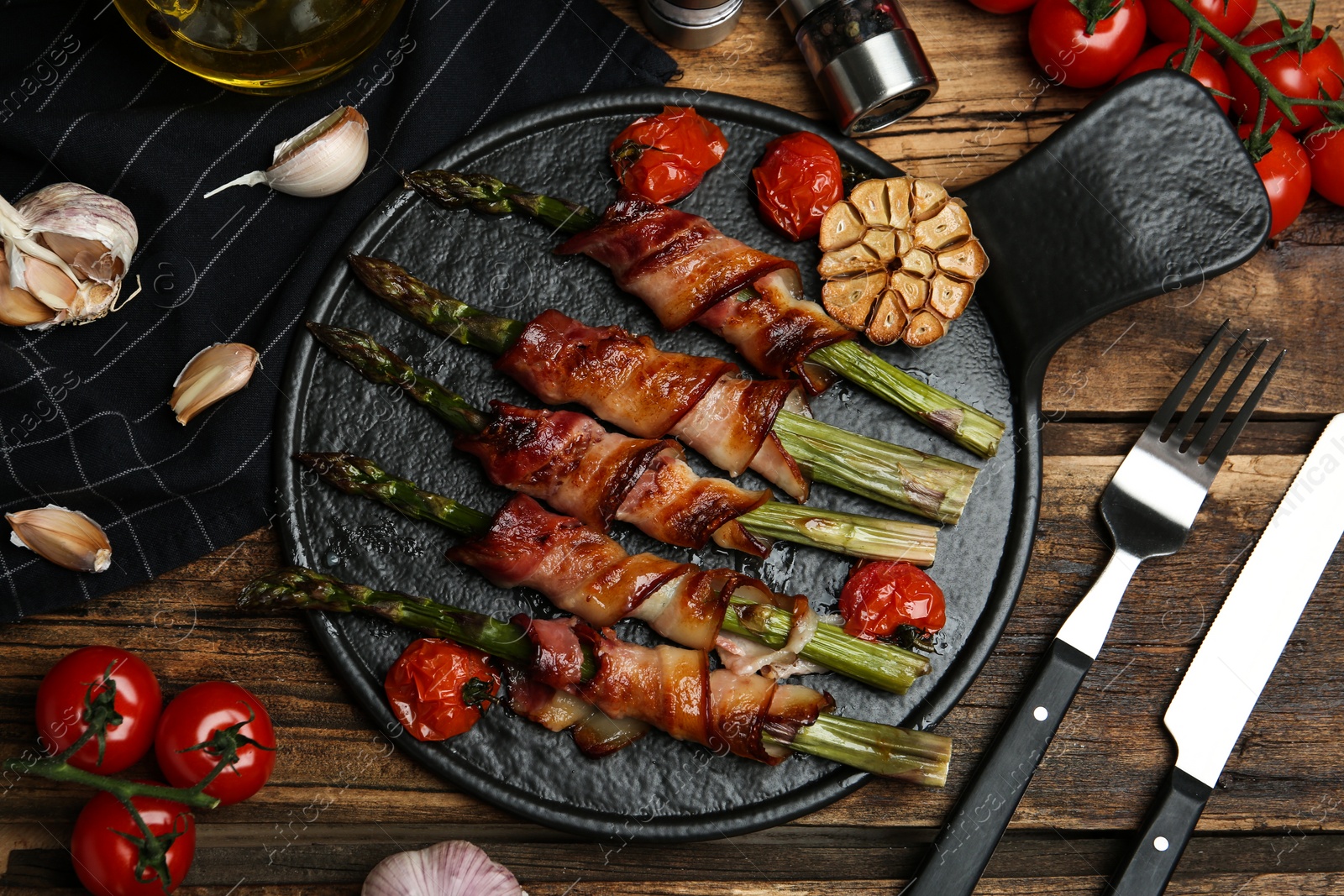 Photo of Oven baked asparagus wrapped with bacon on wooden table, flat lay