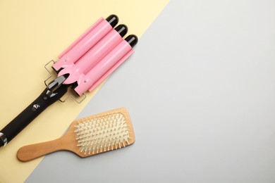 Hair brush and triple curling iron on color background, flat lay. Space for text
