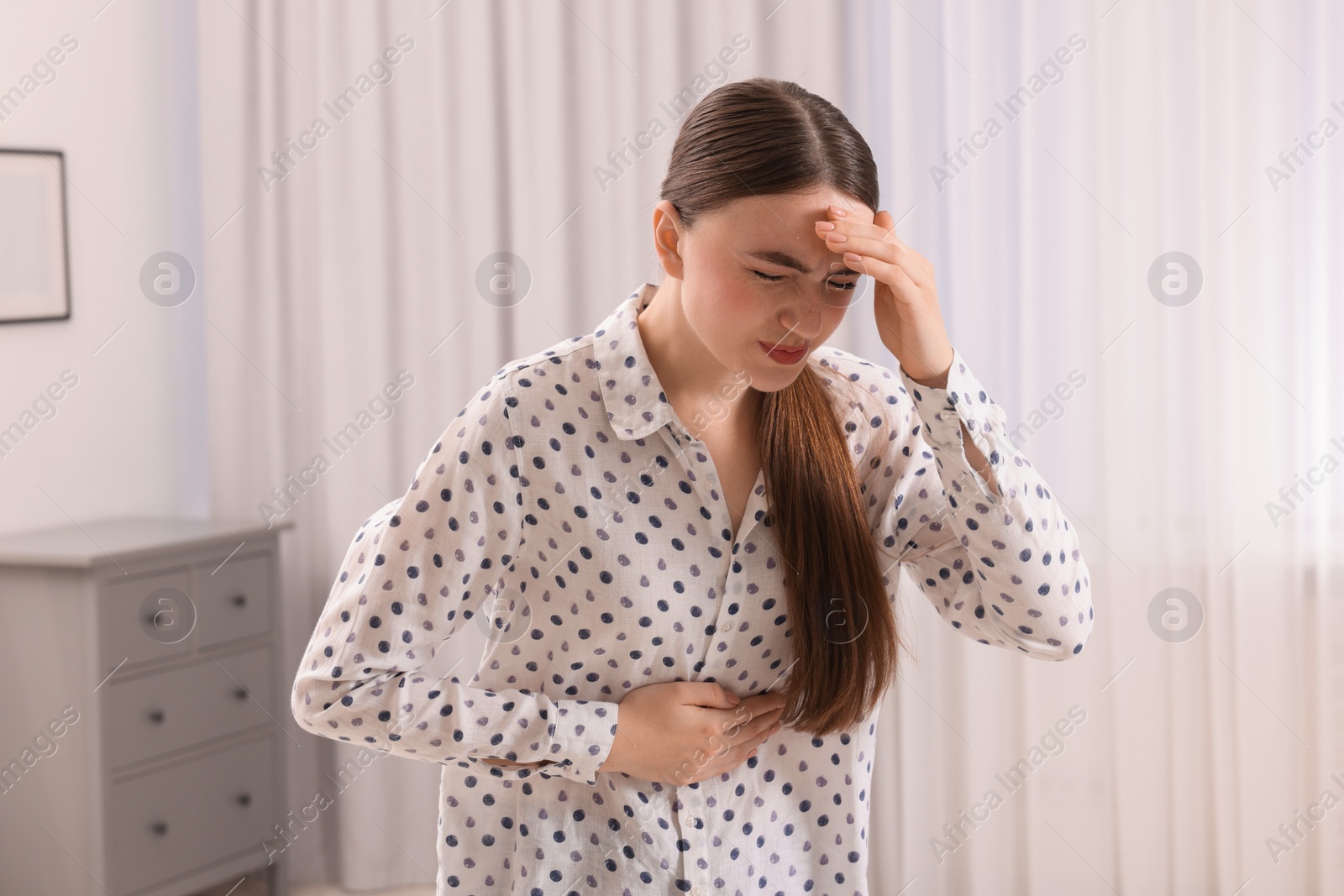 Photo of Young woman suffering from stomach pain at home