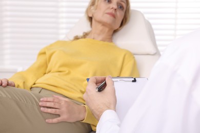 Photo of Doctor with clipboard consulting patient in clinic, closeup