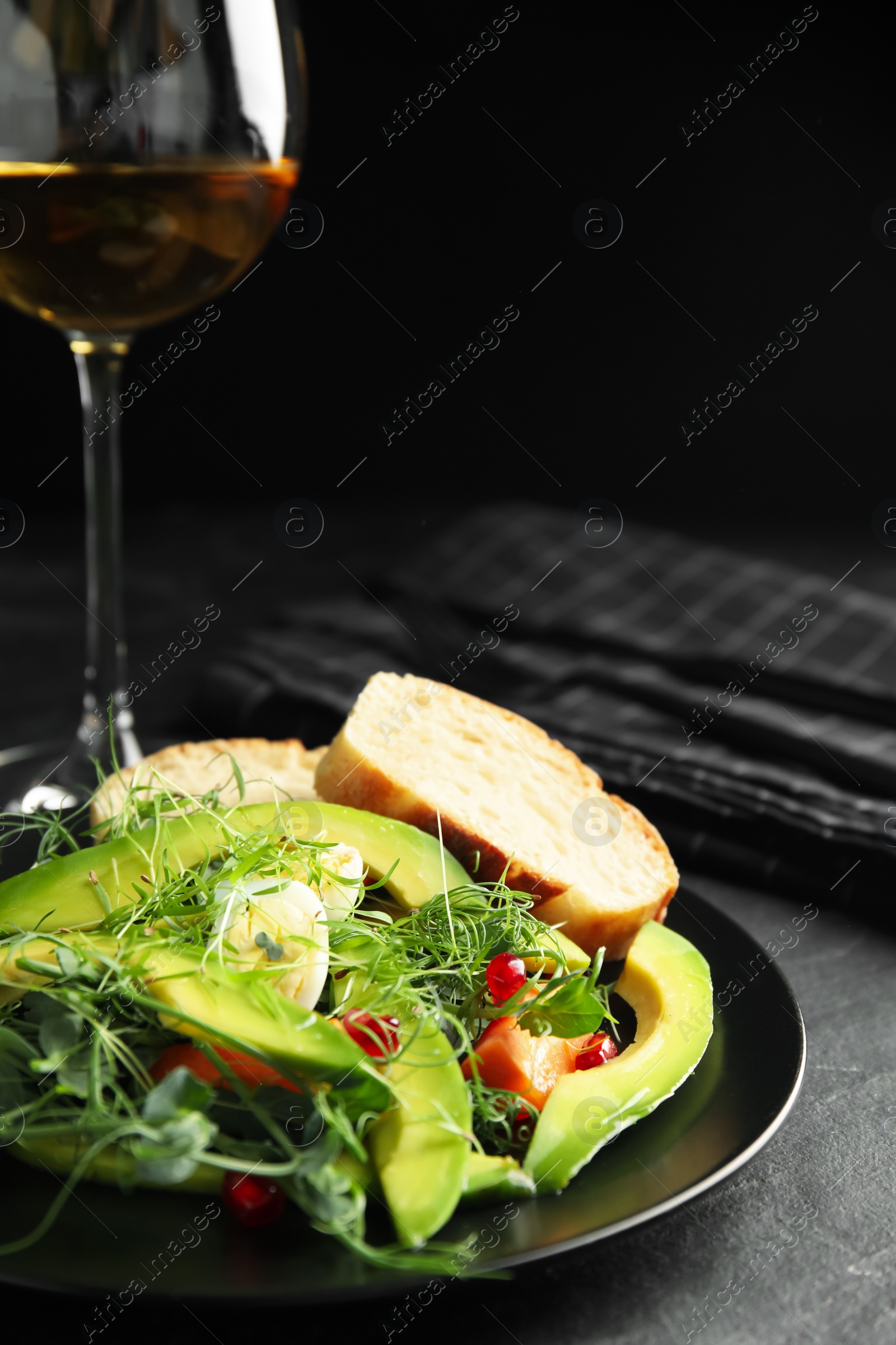 Photo of Salad with fresh organic microgreen in plate on black table, closeup