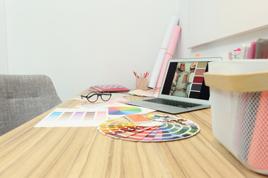 Photo of Designer's workplace with modern laptop and color palettes 