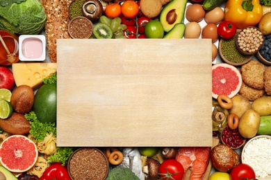 Photo of Wooden board on pile of different food products, top view with space for text. Healthy balanced diet