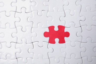 White jigsaw puzzles and red one as background, top view