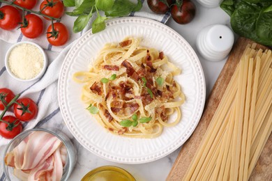 Tasty pasta with bacon and basil on white marble table, flat lay