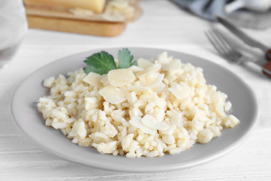 Delicious risotto with cheese on white wooden table, closeup