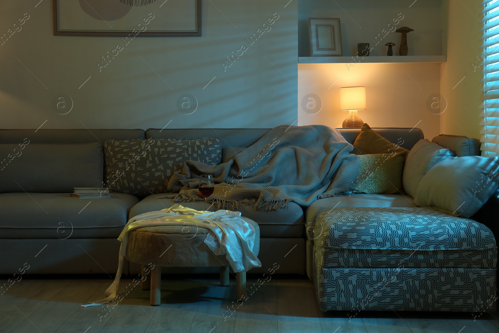 Photo of Stylish room interior with couch and lamp at night