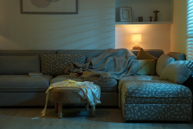 Stylish room interior with couch and lamp at night