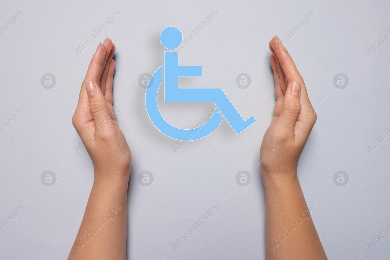 Image of Disability inclusion. Woman protecting wheelchair symbol on light background, closeup