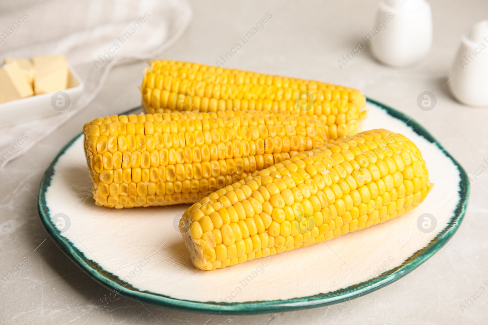 Photo of Delicious boiled corn on light grey marble table