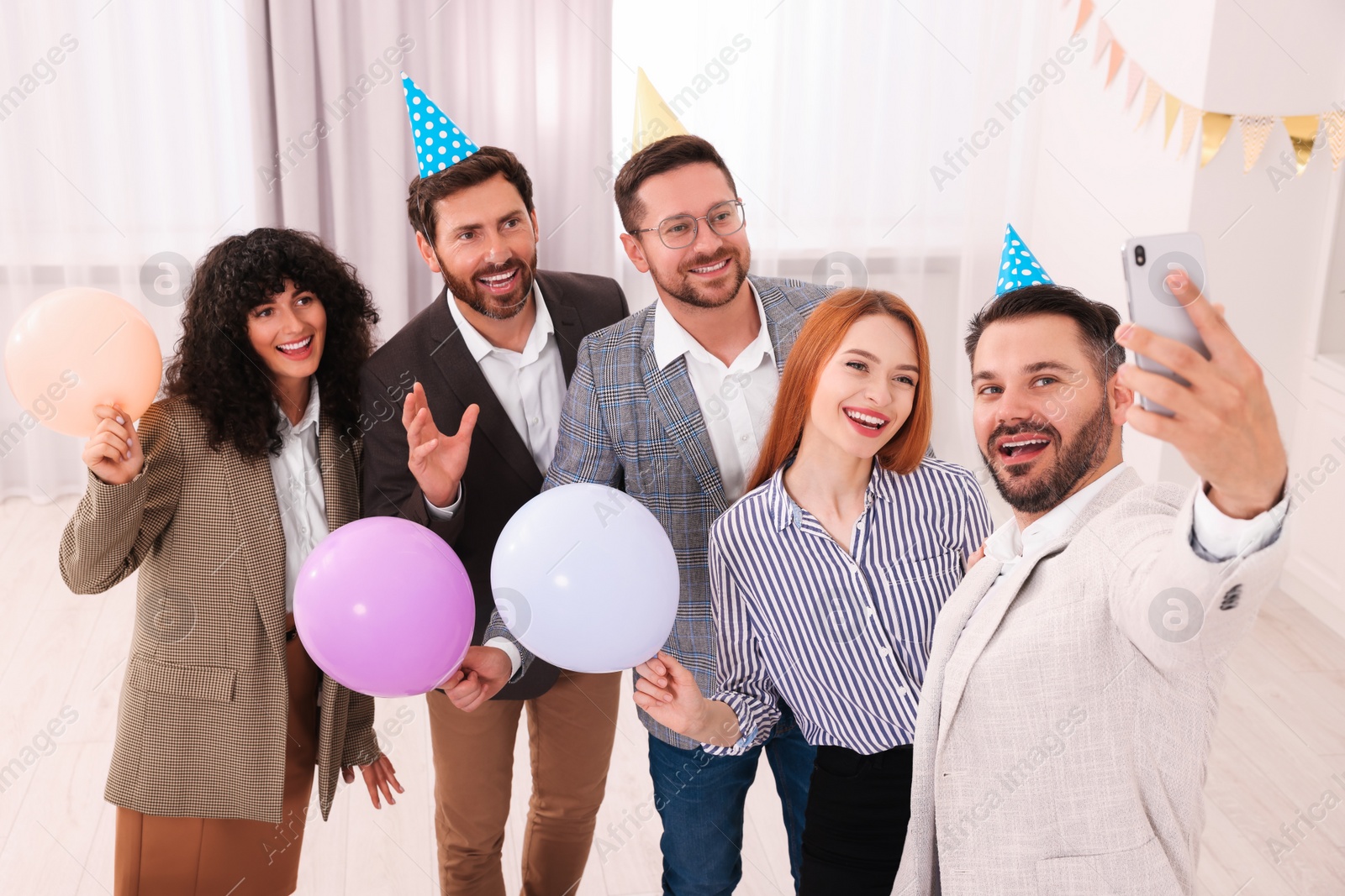 Photo of Coworkers taking selfie during office party indoors