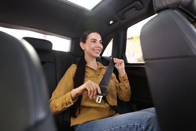 Photo of Woman fastening safety seat belt inside modern car