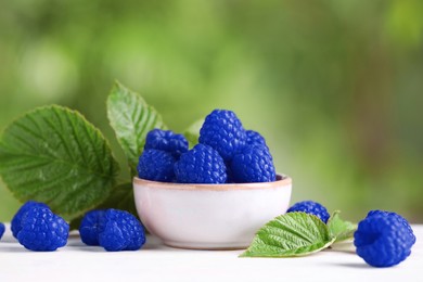 Many fresh blue raspberries in bowl on table