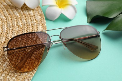 Photo of New stylish elegant sunglasses on turquoise background, closeup