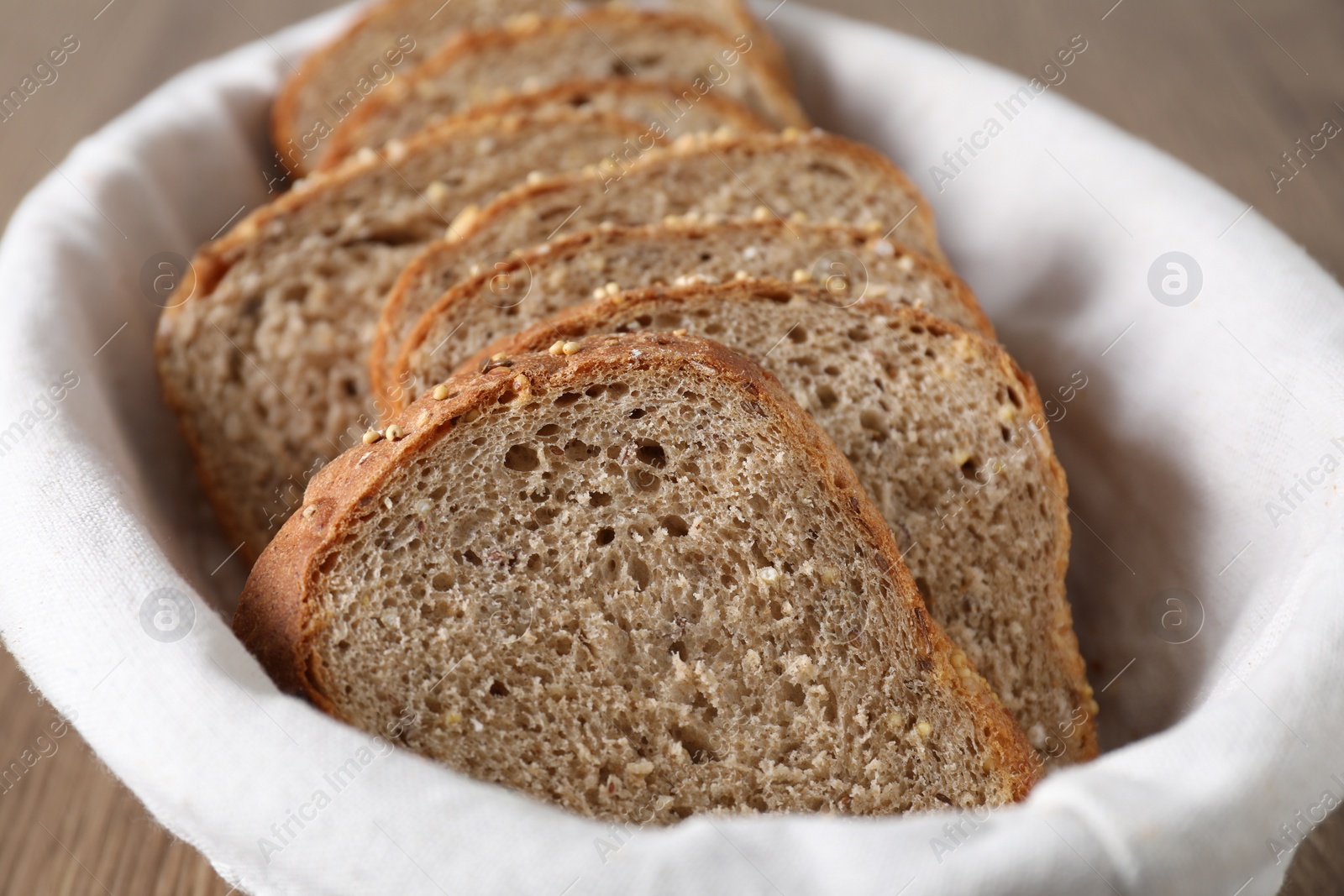 Photo of Slices of fresh bread in basket on table, closeup