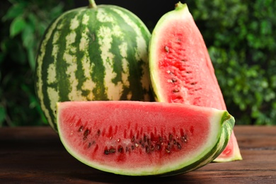 Photo of Whole and cut ripe watermelons on wooden table