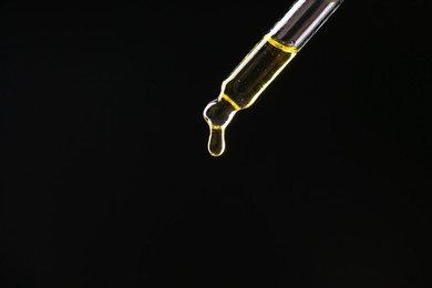 Photo of Dripping tincture from pipette on black background, closeup. Space for text